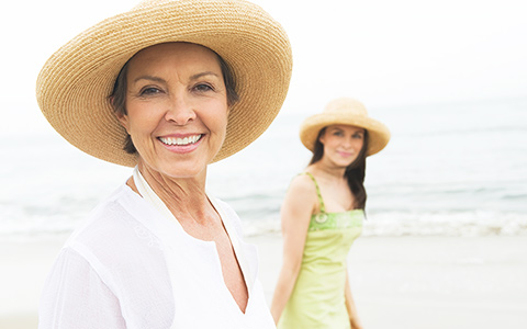 A selfie of a senior woman and her daughter with the ocean in the background.